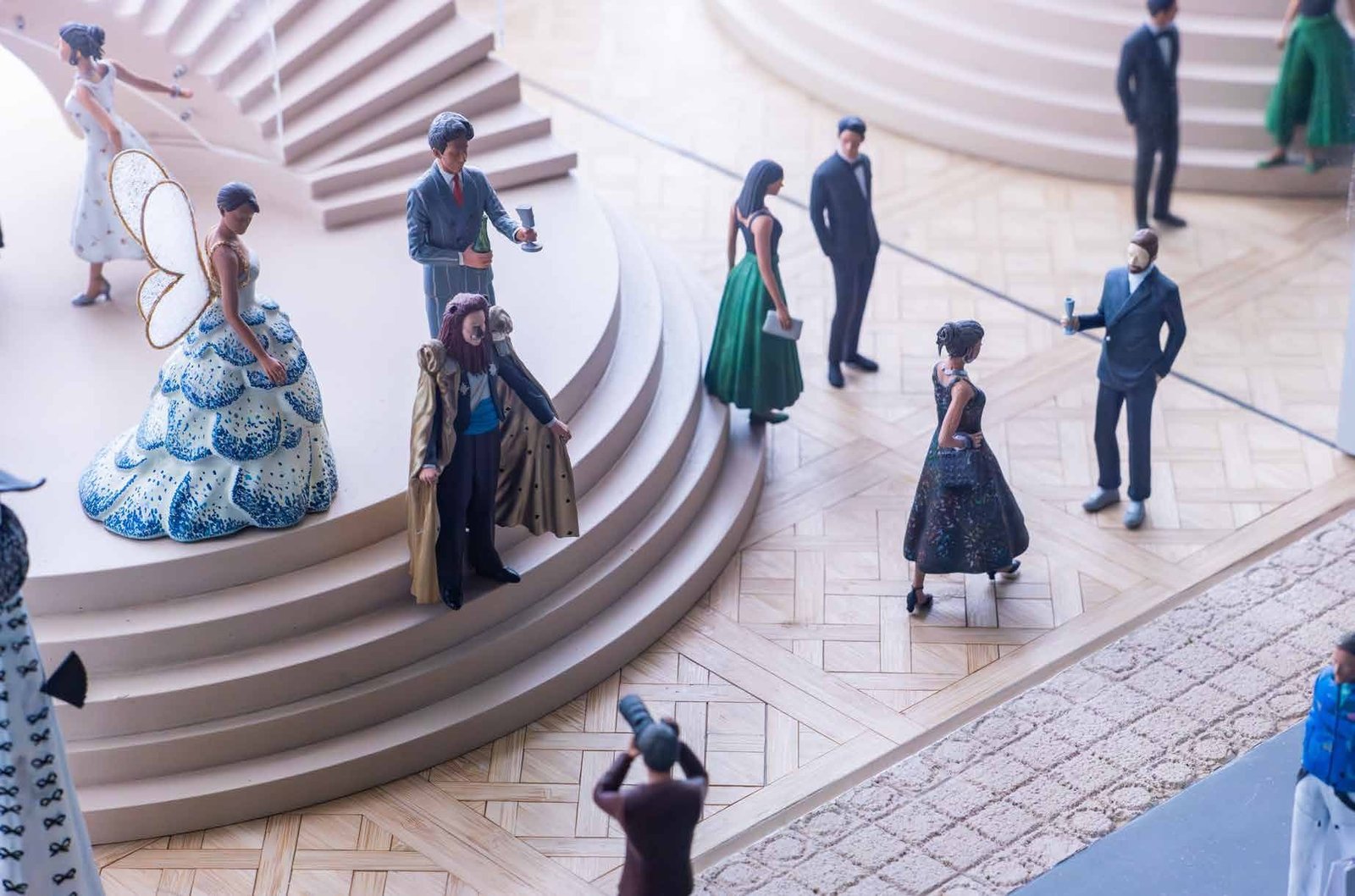 Miniature figurines in evening wear arranged on a curved staircase model.