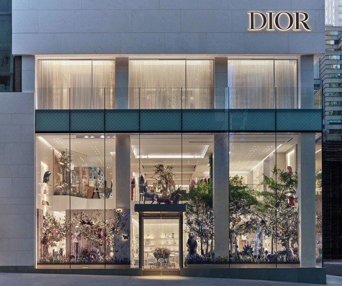 Illuminated storefront windows filled with flowering-garden displays and a horse figure.