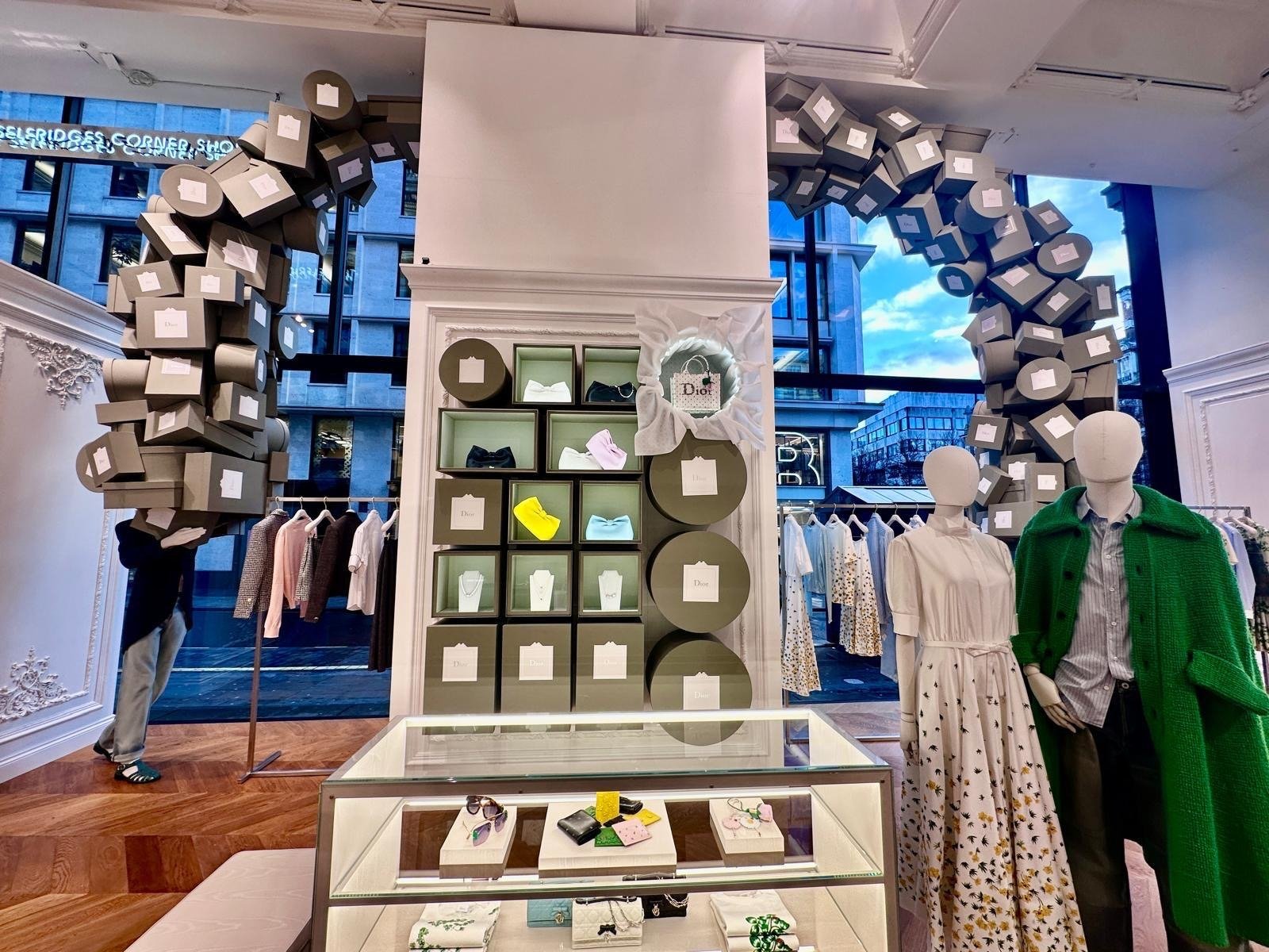 In-store display of arched grey boxes framing a shelved wall of accessories and mannequins.