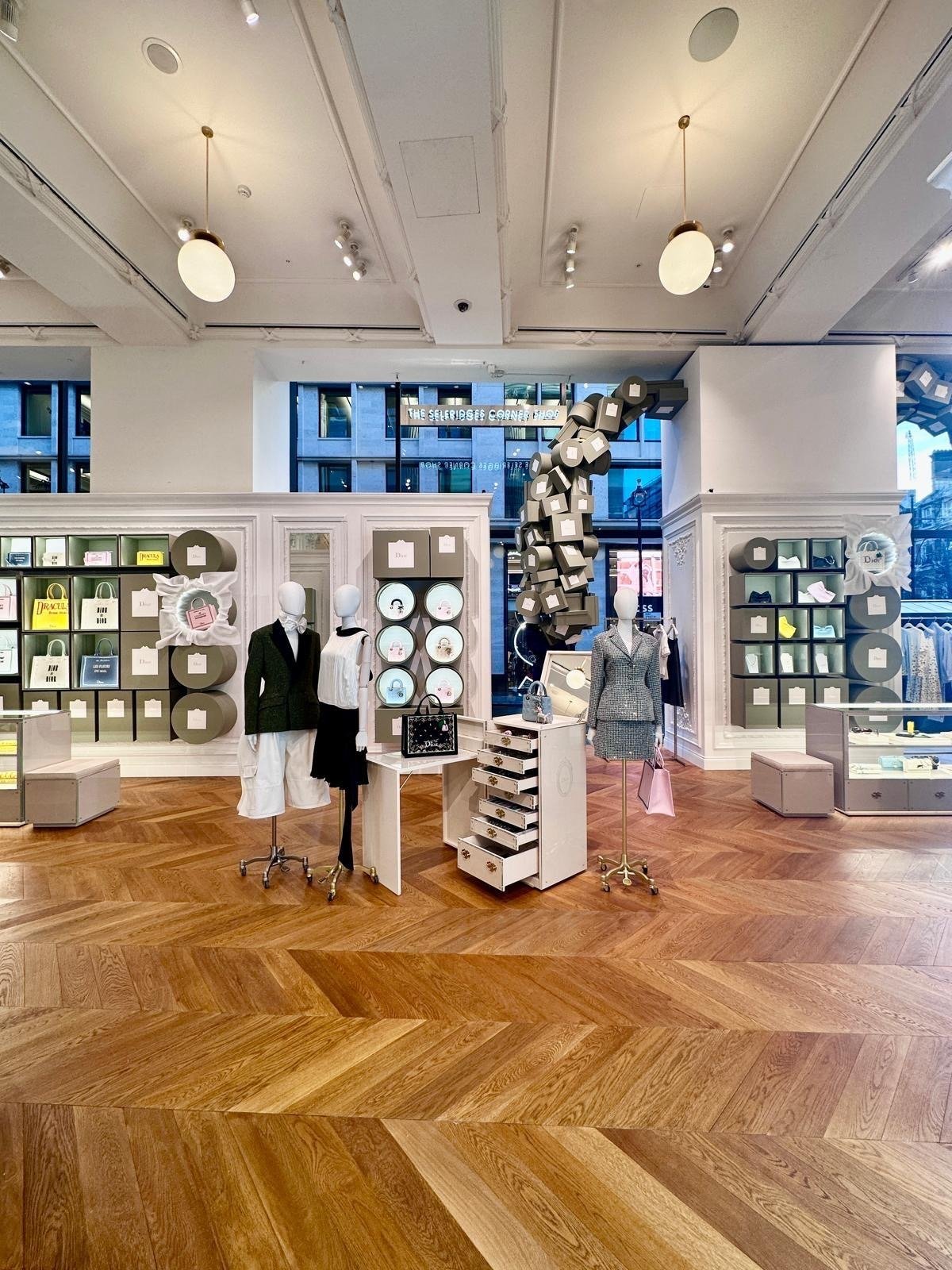 Interior boutique floor in herringbone wood with mannequins and grey box-tower displays.