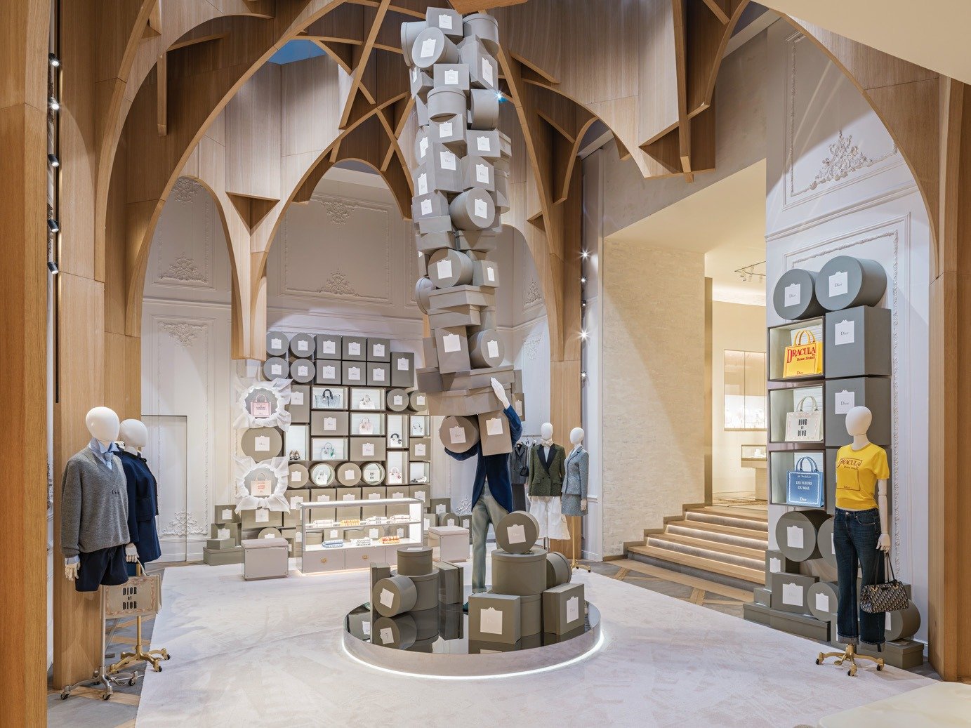 Vaulted interior with a tower of grey boxes above mannequins and shelved displays.