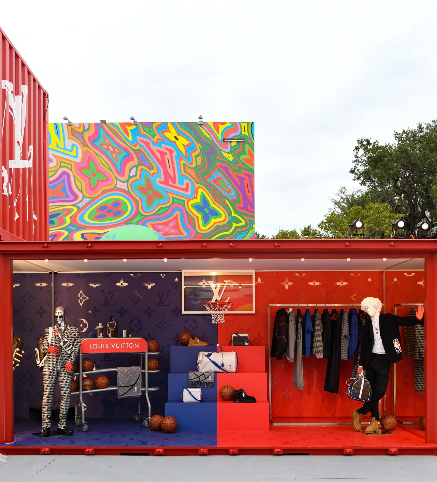 Open red container styled as a boutique with basketball props and a colourful monogram panel above.