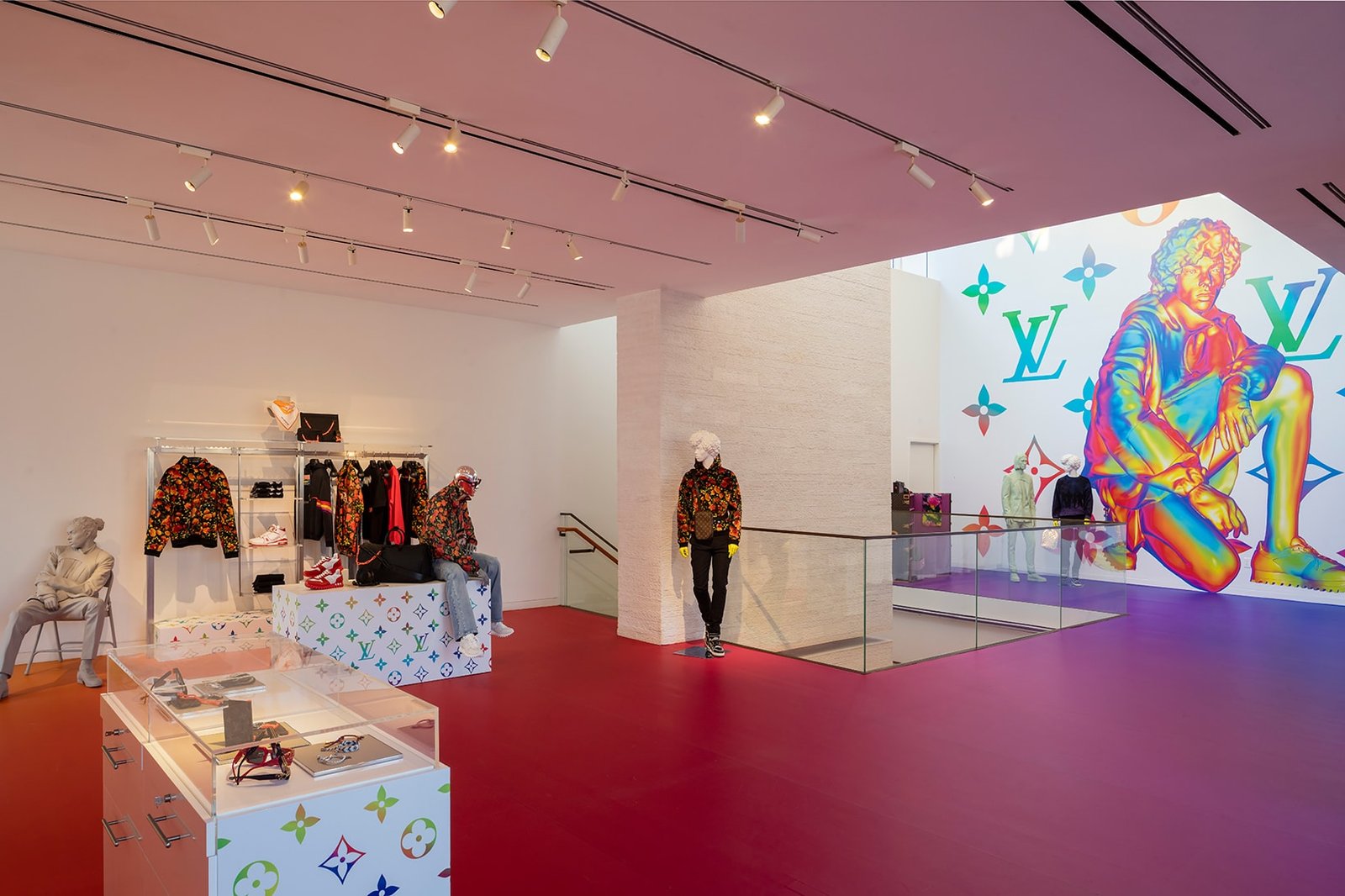 Showroom with red floor, track lighting and monogram plinths under a pink ceiling.