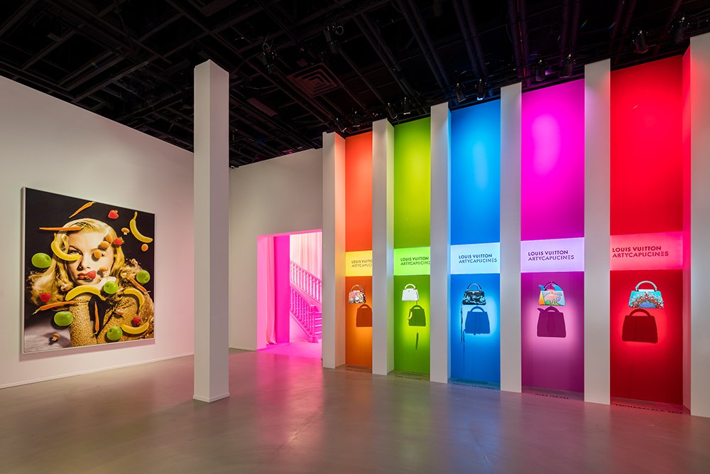 Gallery with vivid coloured niches holding handbags and a large portrait painting on the left.